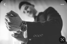 a man in a suit is holding his watch