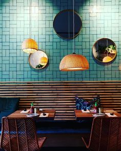 two tables and chairs in a restaurant with round mirrors on the wall above them,