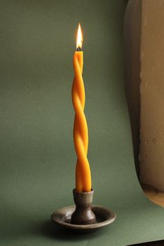 a lit candle sitting on top of a metal plate next to a green wall and floor