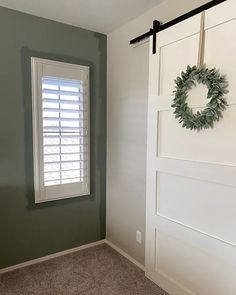 an empty room with a wreath hanging on the wall and a window in the corner