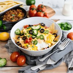 a white bowl filled with nachos, cheese and green peppers on top of a wooden table