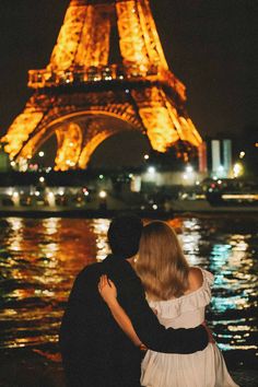 a man and woman standing in front of the eiffel tower