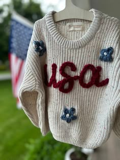 Customized Hand-Embroidered Name Sweaters -  stitched with love and attention to detail. USA design is perfect for 4th of July, flag day and memorial day!  SIZING: These sweaters are intentionally designed to be oversized. For a true-to-size fit, consider sizing down. MATERIAL: Sweaters are 100% Cotton ; please note, some of the yarn may contain wool.  YARN: When placing your order, kindly specify your preferred yarn color choice in the customization box (I have every color yarn under the sun and I will send you options if you would like me too, or a different ).  If no color preference is provided, I will contact you and give you 2 days to respond or I will move forward with using a neutral color that blends best. I'm happy to run with any design freedom you give me!!  SWEATER CARE: I rec Embroidered Kids Clothes, Hand Embroidered Sweater, Embroidered Sweaters, Sweater Care, Sweater Designs, Baby Wishlist, Sweater Ideas, Vinyl Clothing, Usa Design