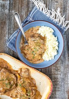 two plates of food with meat and gravy on them next to a bowl of rice