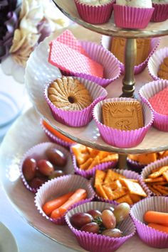 a three tiered tray with cupcakes, crackers and carrots on it