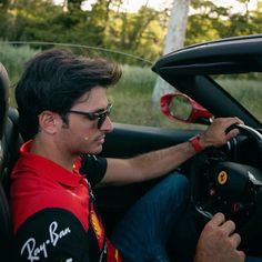 a man sitting in the driver's seat of a car with his hand on the steering wheel