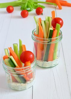 two small glass containers filled with veggies on top of a white table