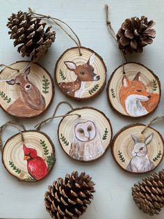 wood slices with painted animals on them and pine cones around the edges, hanging from twine strings