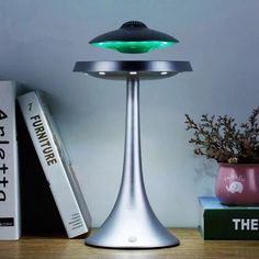 a table lamp sitting on top of a wooden desk next to books and a plant