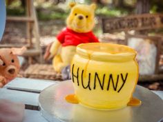 a winnie the pooh birthday cake on a table with two stuffed animals in the background