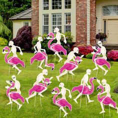 a group of flamingos standing on top of a lush green field next to a house