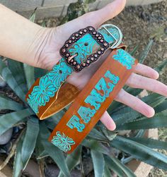 a person's hand holding three different colored leather belts with the words fair trade on them