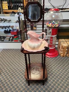 a small table with a pink vase on it and other items in the back ground