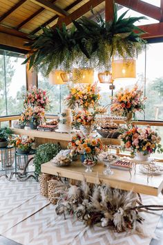 a table topped with lots of flowers next to tall vases filled with greenery