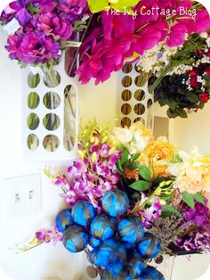 a vase filled with lots of colorful flowers next to a wall mounted air freshener dispenser