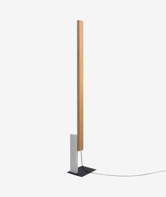 a white and wood floor lamp with a wooden pole attached to the base, on a light gray background