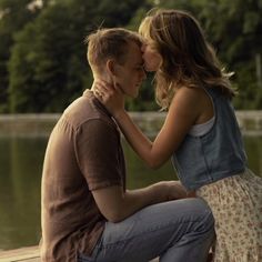 a man and woman sitting on a dock kissing