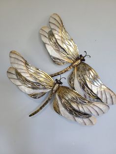 three metal dragonflies mounted to the side of a wall