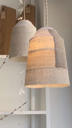 two lamps hanging from the ceiling in a room with white walls and wooden boards on the wall