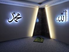 two illuminated arabic letters are on the wall above a carpeted area with a rug