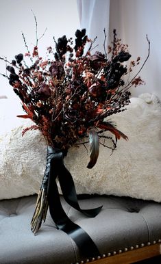 a bouquet of dried flowers sitting on top of a bench next to a white pillow