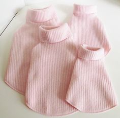 two pink sweaters sitting on top of a white table