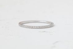 The perfect ring for any look and any occasion. This dainty band features pavé-set diamonds half way through the ring. All other sizes will be made to order. Minimalist Diamond Eternity Band For Everyday, Diamond Minimalist Everyday Eternity Band, Minimalist Everyday Diamond Eternity Band, Everyday Eternity Band With Diamond Accents, Dainty Eternity Band With Diamond Accents, Minimalist Diamond Eternity Band, Minimalist Diamond Half Eternity Band, Minimalist Diamond White Eternity Band, Anniversary Stackable Rings With Pave Setting