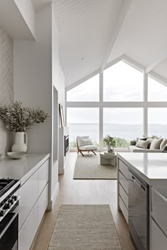 an open kitchen and living room area with large windows overlooking the ocean is pictured in this image