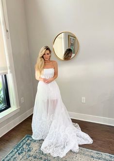 a woman in a white dress standing next to a mirror