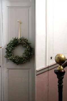 a door with a wreath on it and a candle in the corner next to it