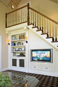 a living room filled with furniture and a flat screen tv mounted on a wall next to a stair case