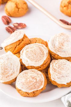 a white plate topped with pumpkin cookies covered in frosting