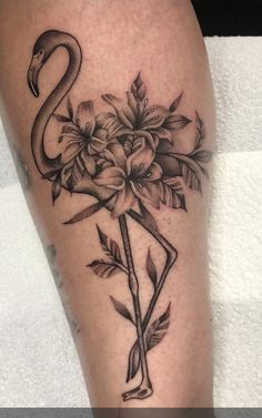 a flamingo tattoo on the leg with flowers