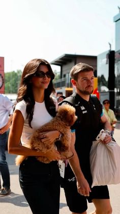 a woman walking down the street holding a teddy bear