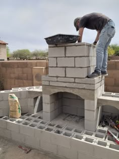 DIY Outdoor Fireplace construction with homeowner finishing the chimney with block and mortar. Standing on structure with mixing bin. Cinderblock construction with block wall behind fireplace. Outdoor Stone Fireplaces, Diy Outdoor Fireplace, Outdoor Fireplace Patio, Backyard Fireplace, Brick Oven, Backyard Remodel, Cinder Block