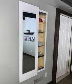 an empty bathroom with a mirror and shelf in it's corner next to the door