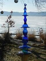 a tall blue glass sculpture sitting on top of a grass covered field next to the ocean