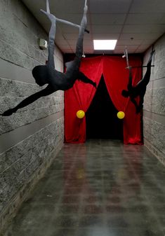 two people doing acrobatic tricks in an empty room with red drapes