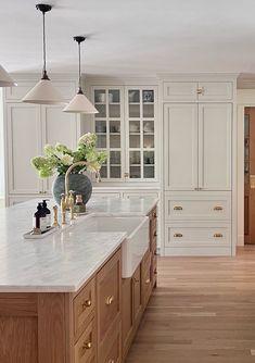 a large white kitchen with wooden floors and cabinets on both sides, along with an island in the middle