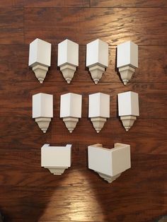 eight white boxes are arranged on a wooden surface, with one missing the top part