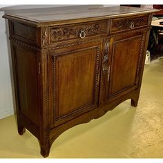 an old wooden cabinet with carvings on the doors and drawer pulls is shown in this image