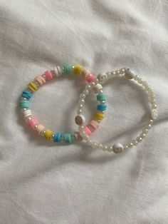 two bracelets with different colored beads on a white sheet