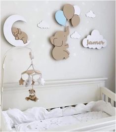 a baby crib with teddy bears hanging from it's hooks and clouds on the wall