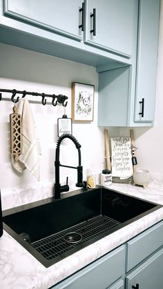 a kitchen sink under a black faucet next to blue cabinets