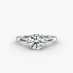 a white gold engagement ring with three stones on the band and an oval center stone