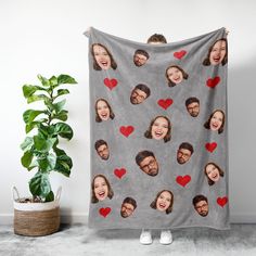 a blanket with many faces and hearts on it next to a potted green plant