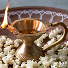 a brass oil lamp with white flowers around it