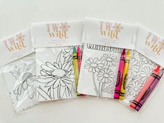 four coloring books with markers in them on a white surface, one is empty and the other has flowers