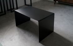 a black desk sitting in the middle of a room next to a stair case and table