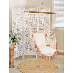 a white hammock with pink tassels on it in front of a window